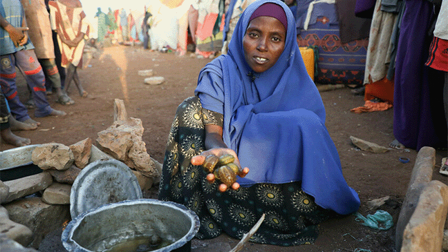 displaced woman in somalia holding out stones hunger