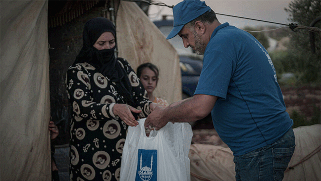 islamic relief representative giving a bag of qurbani meet to a syrian female refugee