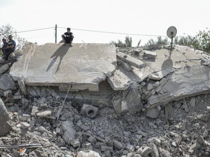 civilians sitting on destroyed houses in Gaza