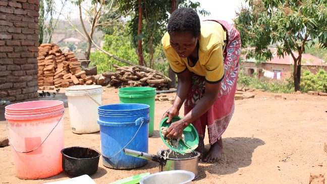 a young woman in malawi drawing water from a borehole