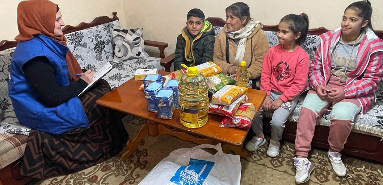 Islamic Relief staff member sat with Albanian family, with staple food items on the table