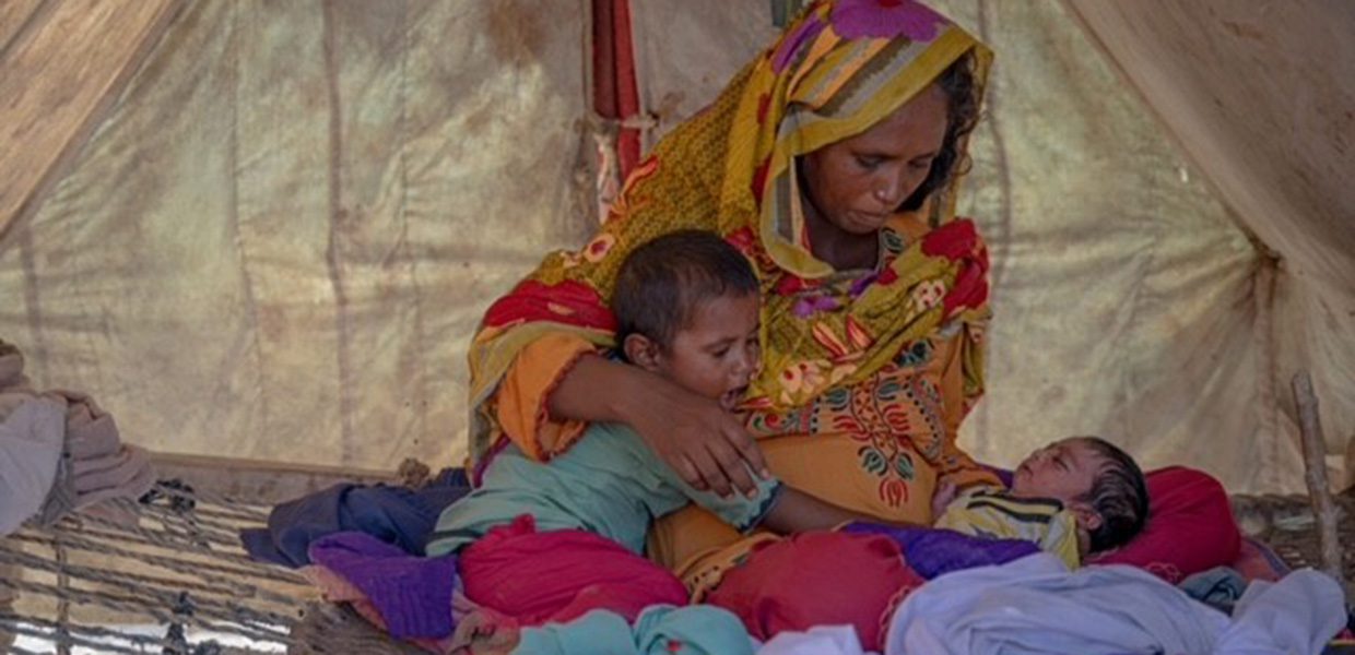 Mother holding her children in a tent.