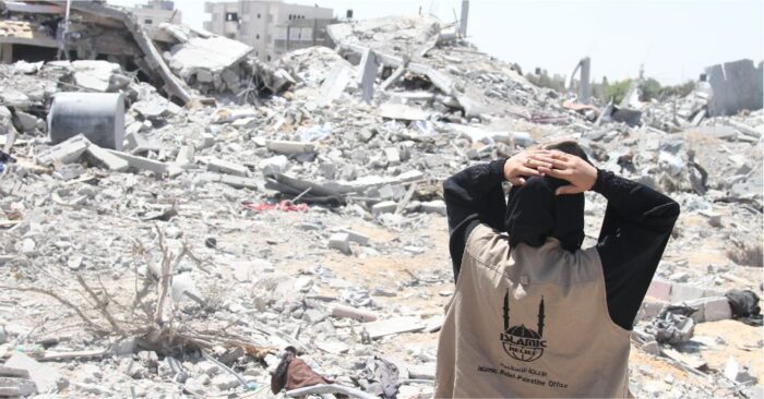islamic relief palestine female staff overlooking destroyed buildings and rubble in gaza