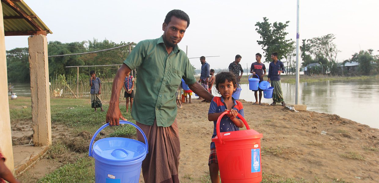 A father and daughter carrying water buckets.