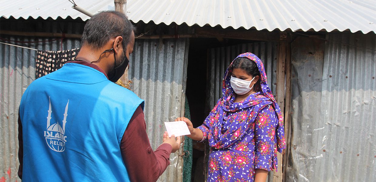 Islamic Relief staff member handing food voucher to lady