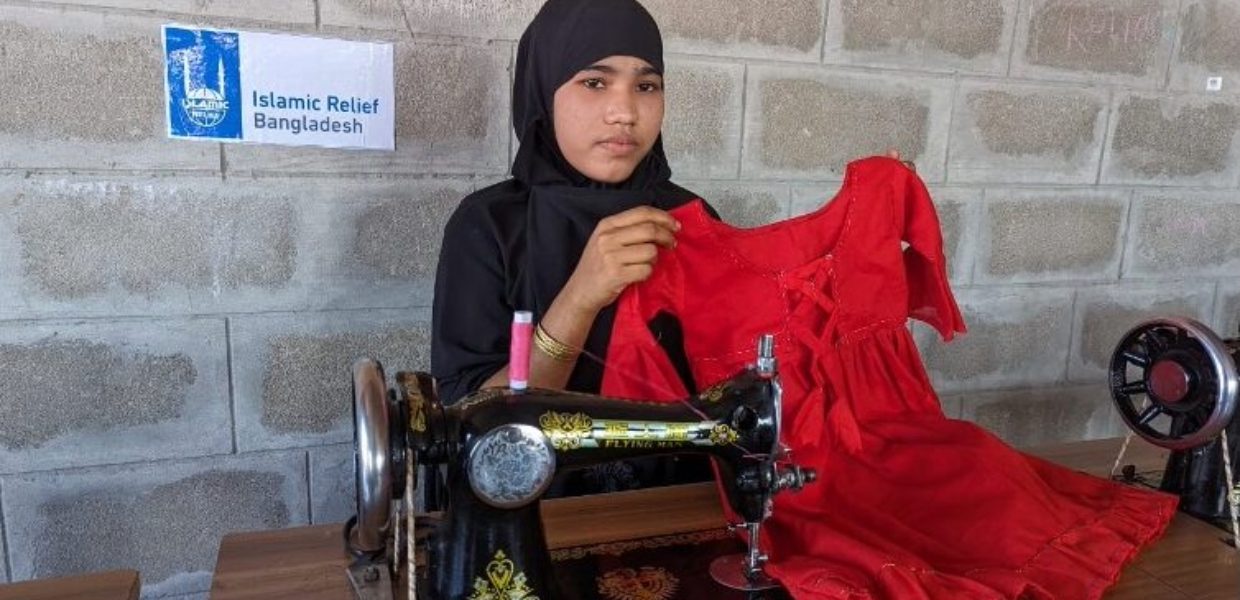 a young teenage girl from bangladesh holding a red dress she sew