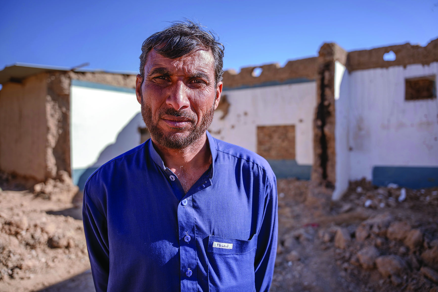 a pakistani man wearing a blue top named sher looking to camera