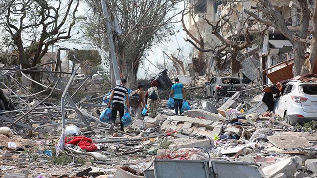 a family in gaza fleeing and walking over destroyed buildings