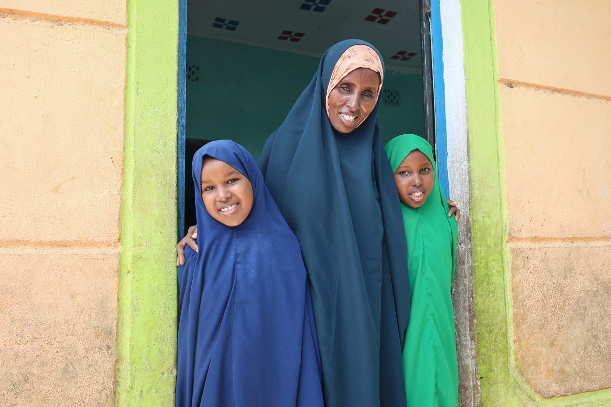 a woman and her two children at a doorway, orphan family sponsorship by islamic relief