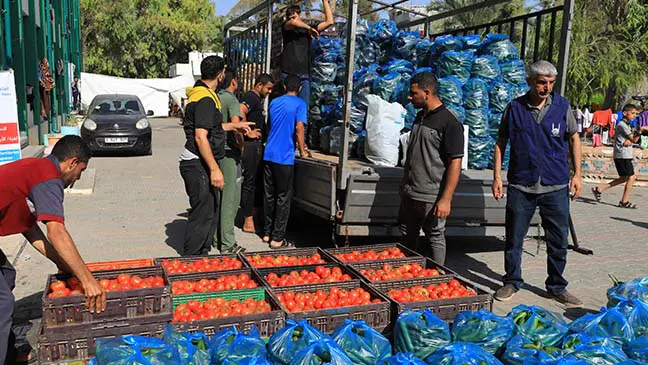 men unloading crates of fresh produce from truck in gaza