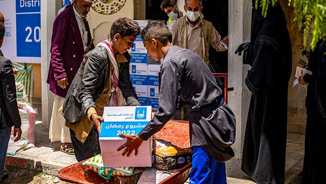 two boys in yemen arranging the food items they received in their food pack from islamic relief