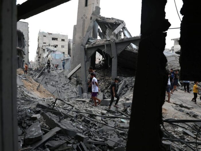 men walking amongst debris from destroyed buildings in gaza