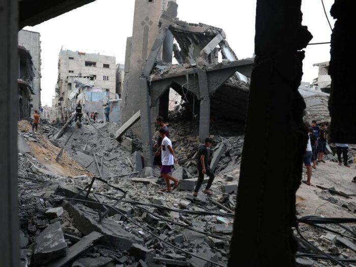 men walking amongst debris from destroyed buildings in gaza