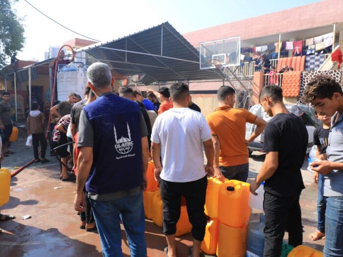 islamic relief staff and men in gaza palestine queueing to collect clean water in their water containers