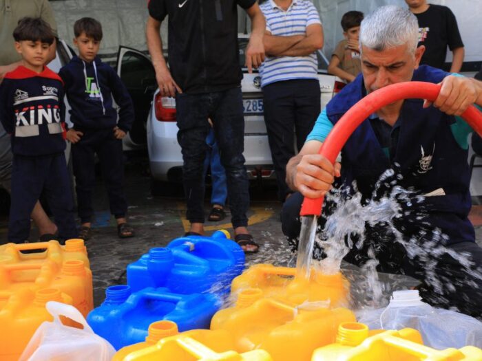 islamic relief teams in gaza filling water containers with clean water to distribute to affected people