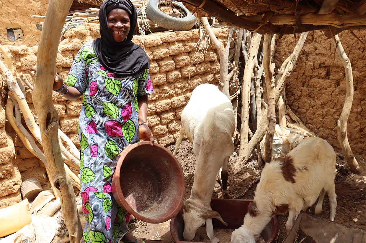 a women smiling next to two goats feeding goat farms