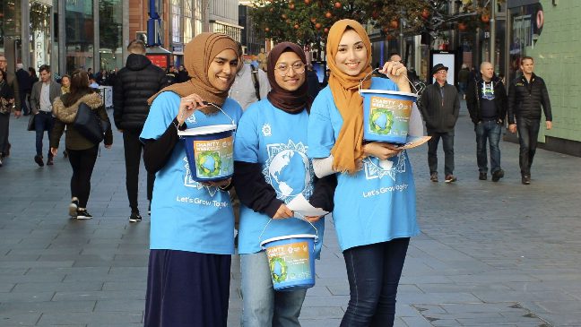 group of female volunteers in charity week t-shirts holding buckets and fundraising for charity week islamic relief
