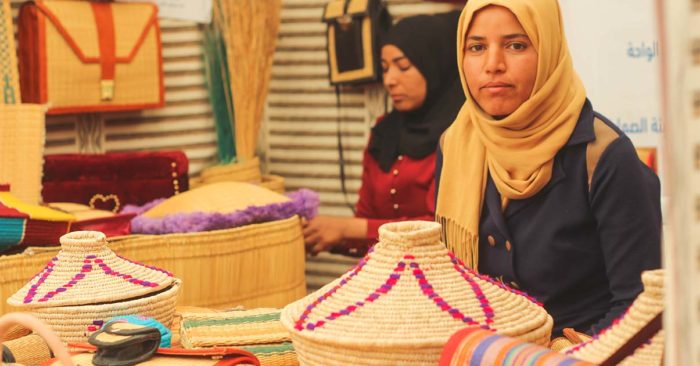 a woman sat with handmade baskets laid out in front of her handicraft training