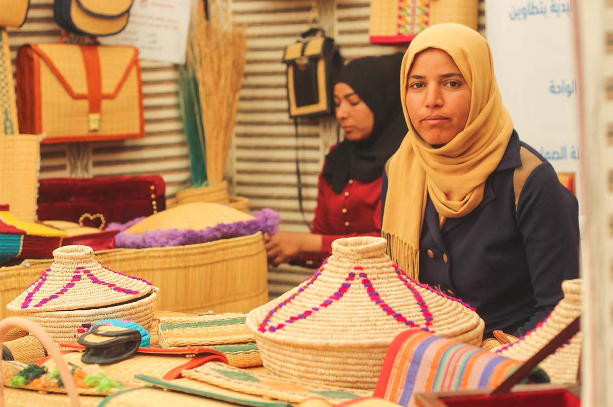 a woman sat with handmade baskets laid out in front of her handicraft training