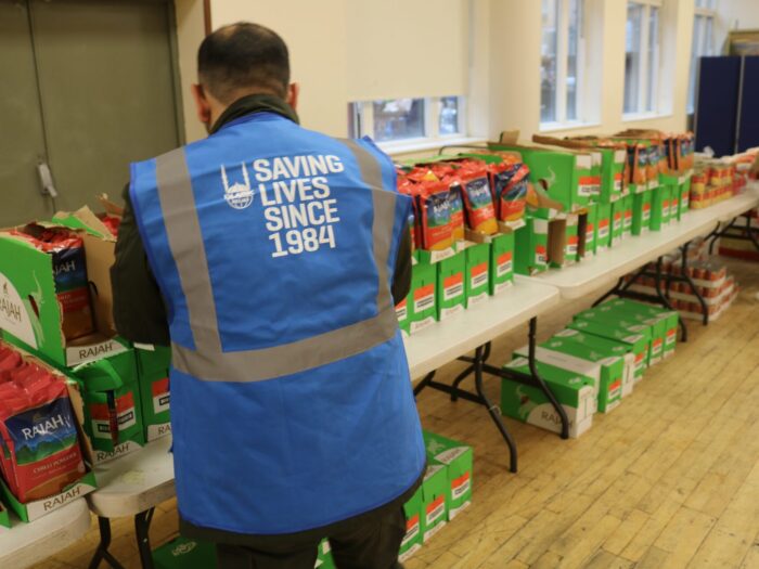 Islamic Relief staff member alongside tinned food items.