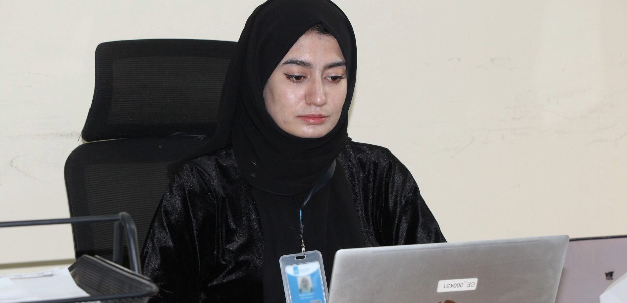 an afghan girl looking out onto her laptop