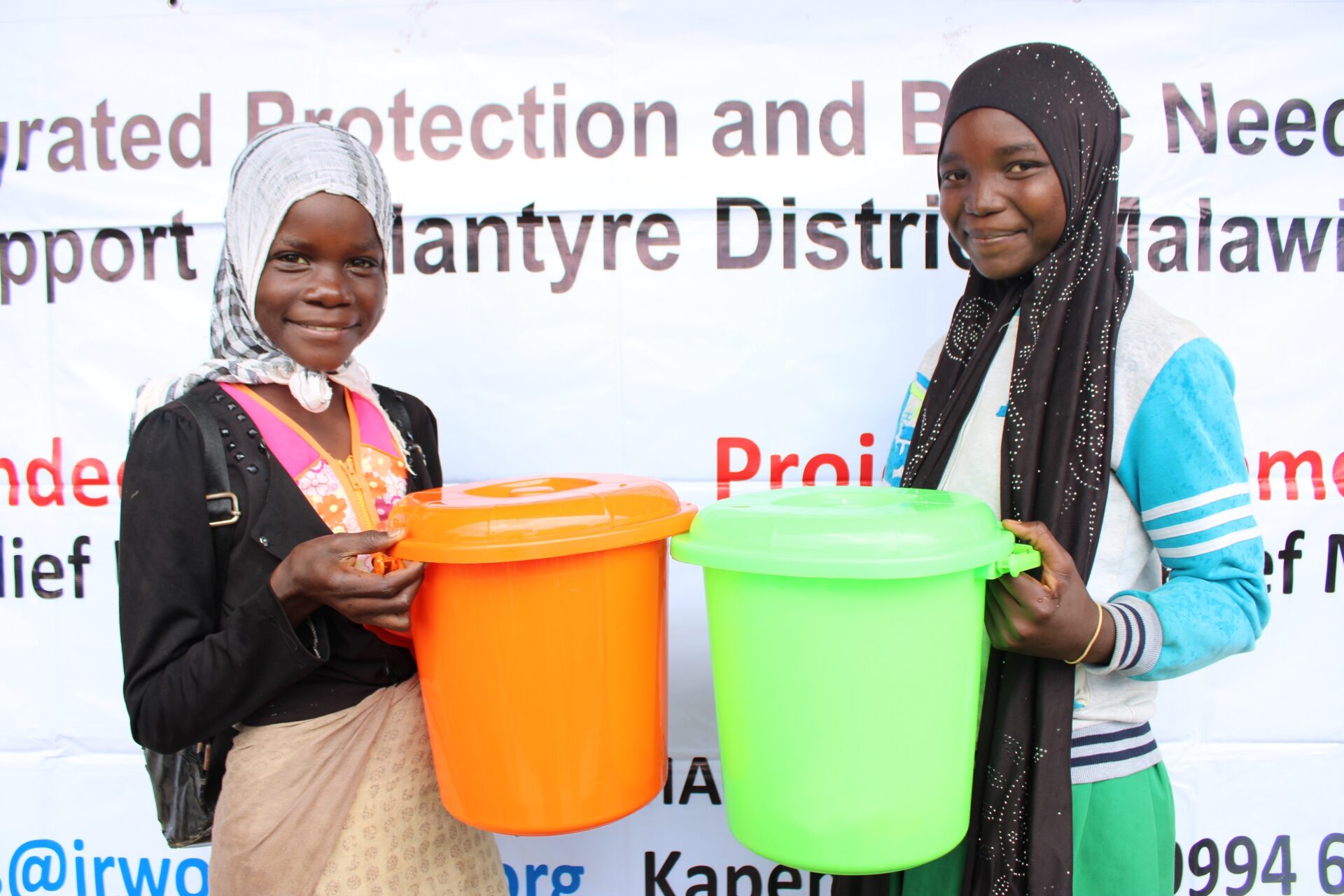 Two girls holding their hygiene kits and smiling at the camera.