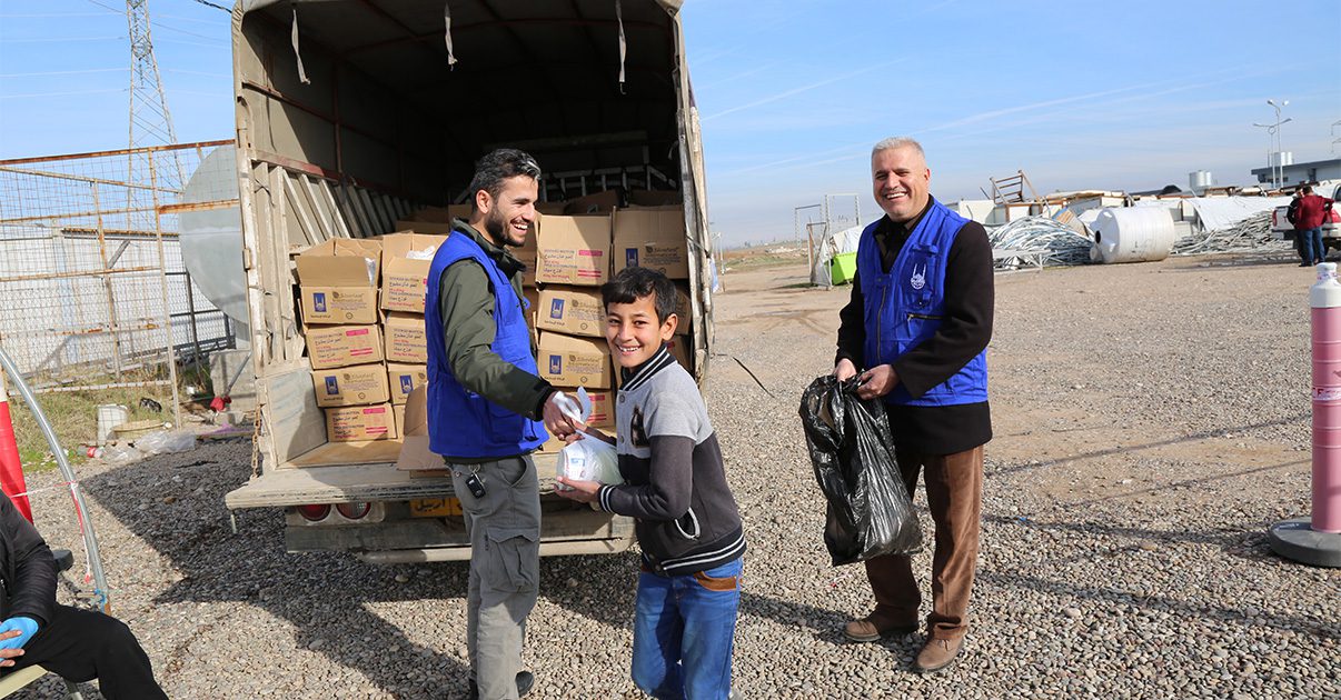 Boy receiving food package from Islamic Relief staff member