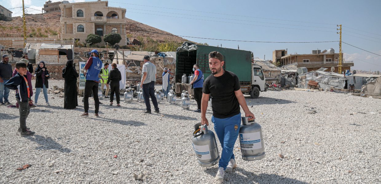 a person carrying two fire extinguishers to distribute to syrian refugees in a camp in lebanon