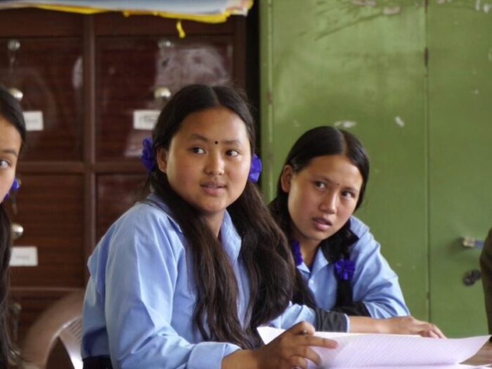 a young girl from nepal sat in the classroom with her peers