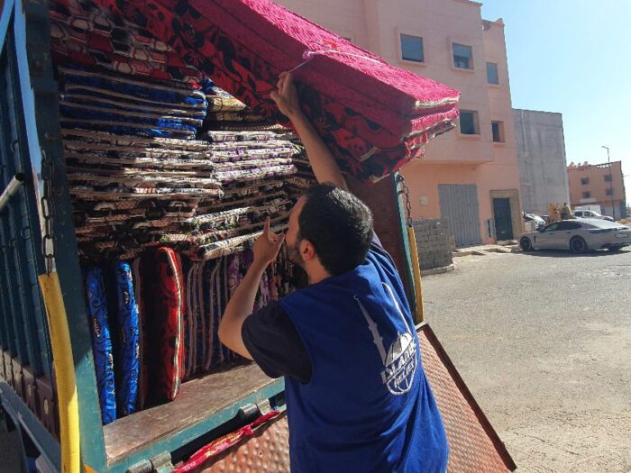 man in blue islamic relief jacket loading a truck with mattress to be distributed to victims of the morocco earthquake