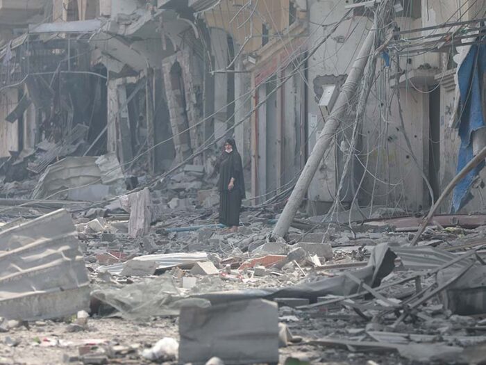 a woman standing amongst debris from destroyed buildings in gaza