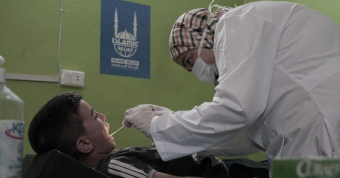 a female nurse looking into the mouth of a young child orphan medical care islamic relief