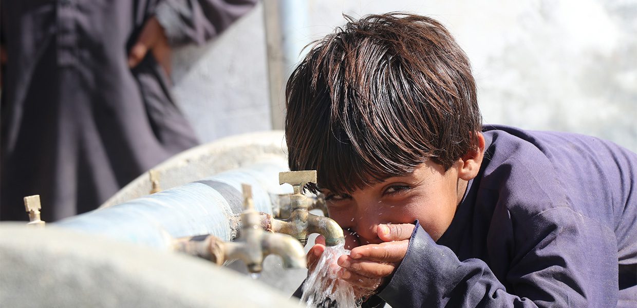 Young boy drinking water from a tap