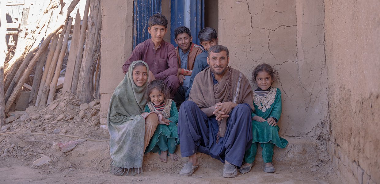 Family sat together and smiling outside their home