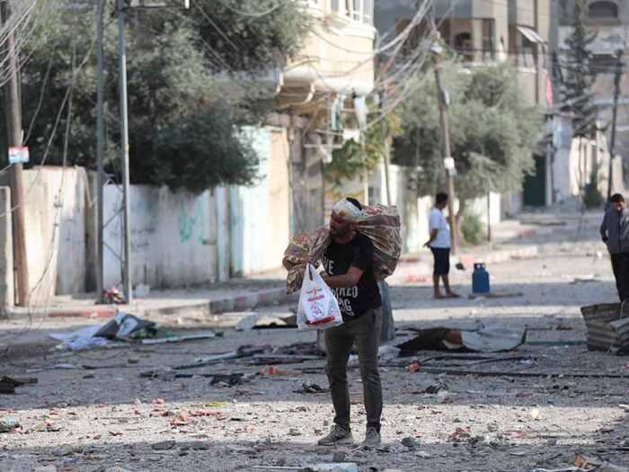 a palestinian man with a head injury holding bags of belongings as he evacuates in gaza