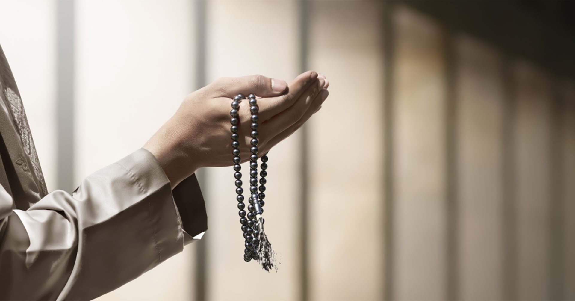 man with hands open infront of him for dua with prayer beads (tasbih) in his hand prayer timetables huddersfield