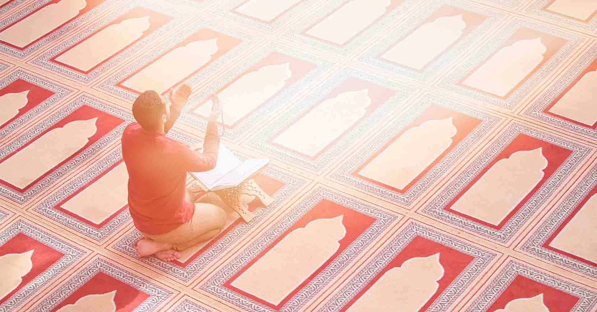 man performing prayer salah dua with an open quran prayer timetables luton