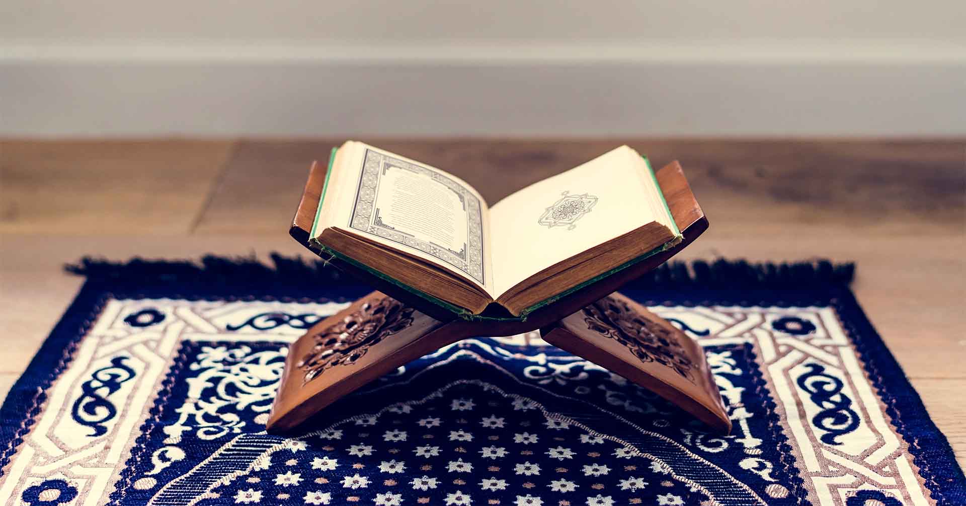 open quran on quran stand on a blue prayer salat mat prayer timetables manchester