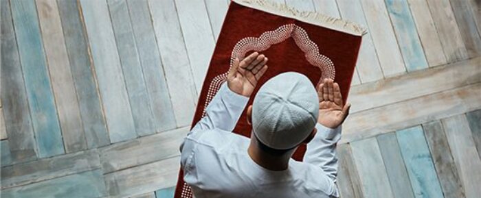 man doing dua on red prayer mat during prayer salah prayer timetables