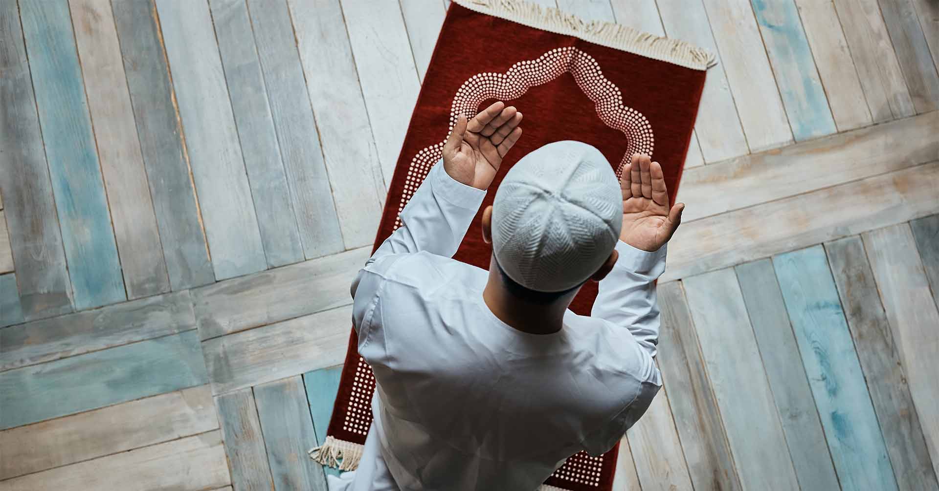 man doing dua on red prayer mat during prayer salah prayer timetables stoke