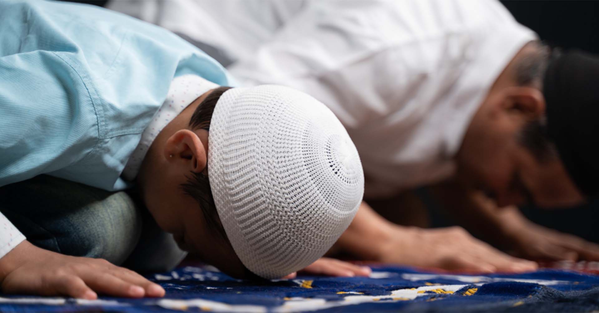 elderly man and young boy on prayer mats in sujood position prayer timetables bradford