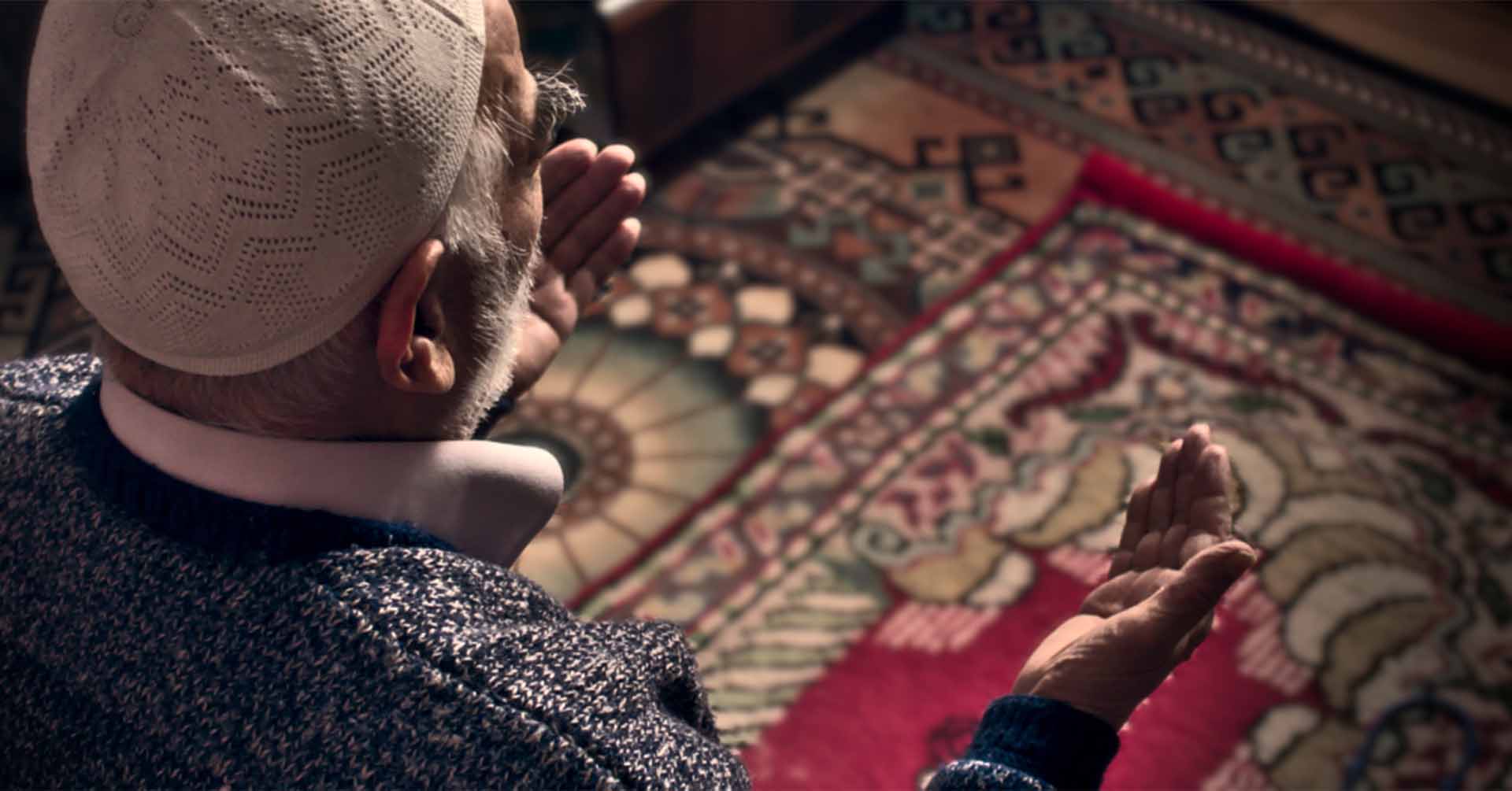 man on prayer mat with hands open in front of him offering dua prayer timetables coventry