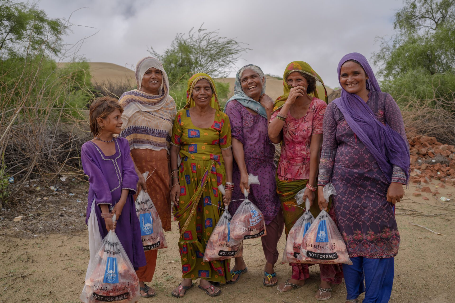 a group of women in pakistan holding a bag of qurbani meat each