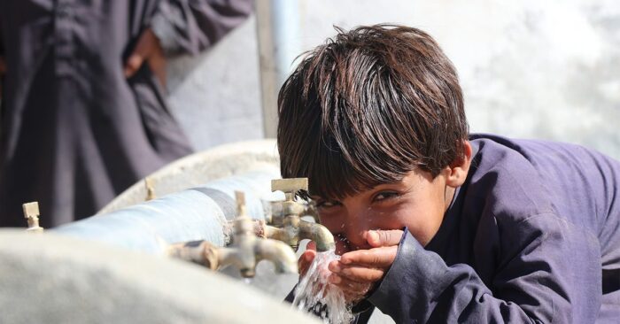 A child drinks from water source provided by Islamic Relief sadaqah