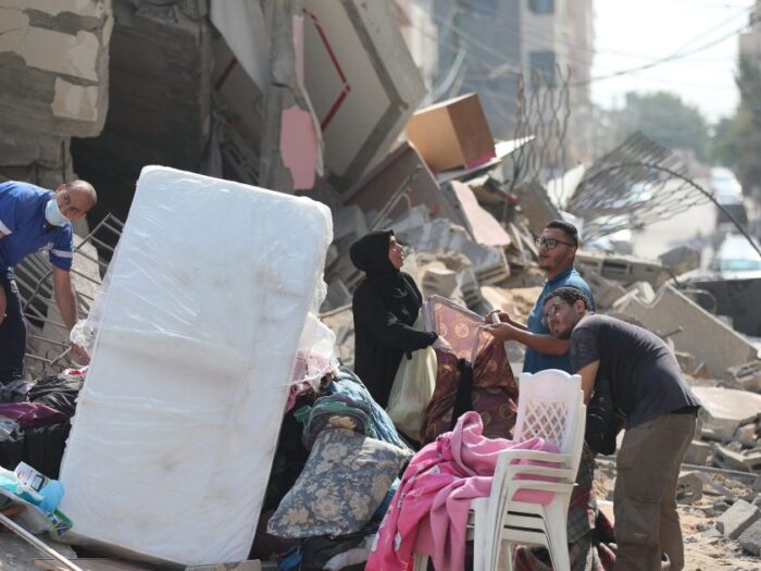 a group of people in gaza standing next to debris from destroyed buildings following recent airstrikes