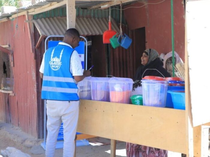 an islamic relief staff member visiting a woman at her shop who has been supported by islamic relief as part of a project to help orphan families with cash grants