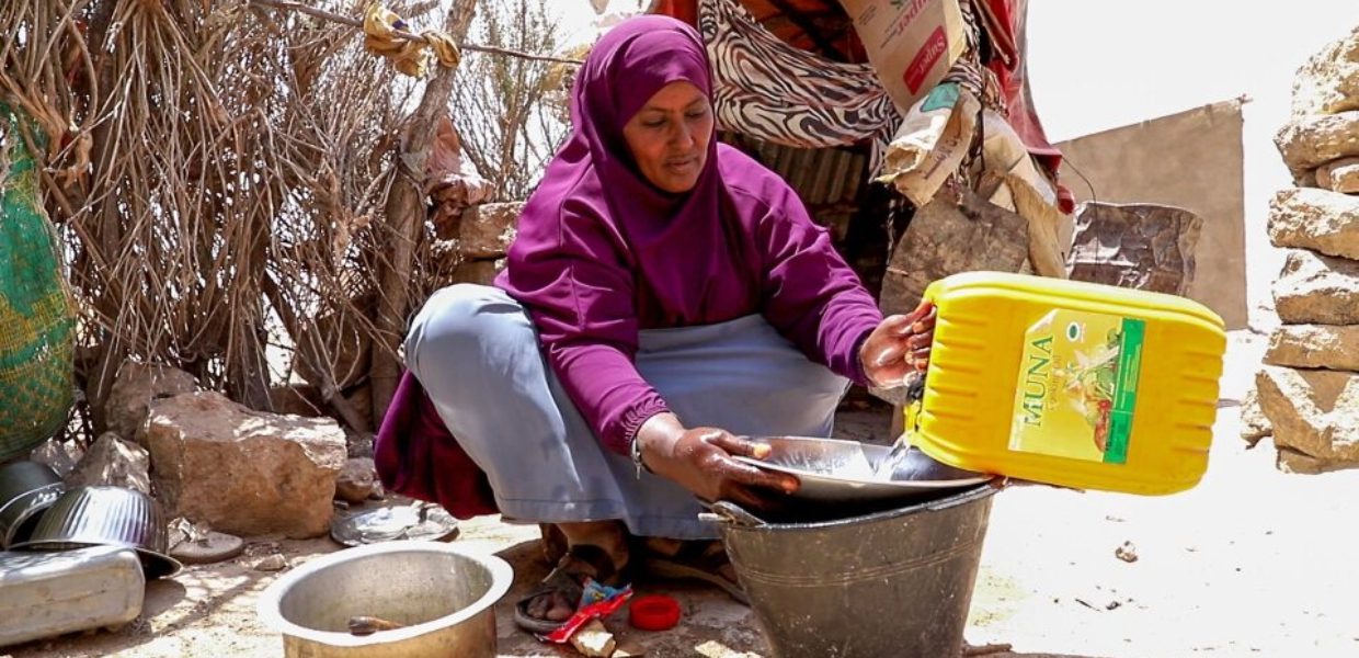 a person in a purple head scarf washing her hands