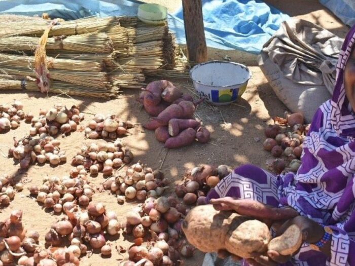 a sudanese woman smiling while holding potatoes