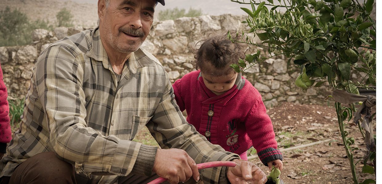 Man tending to his crops with young child