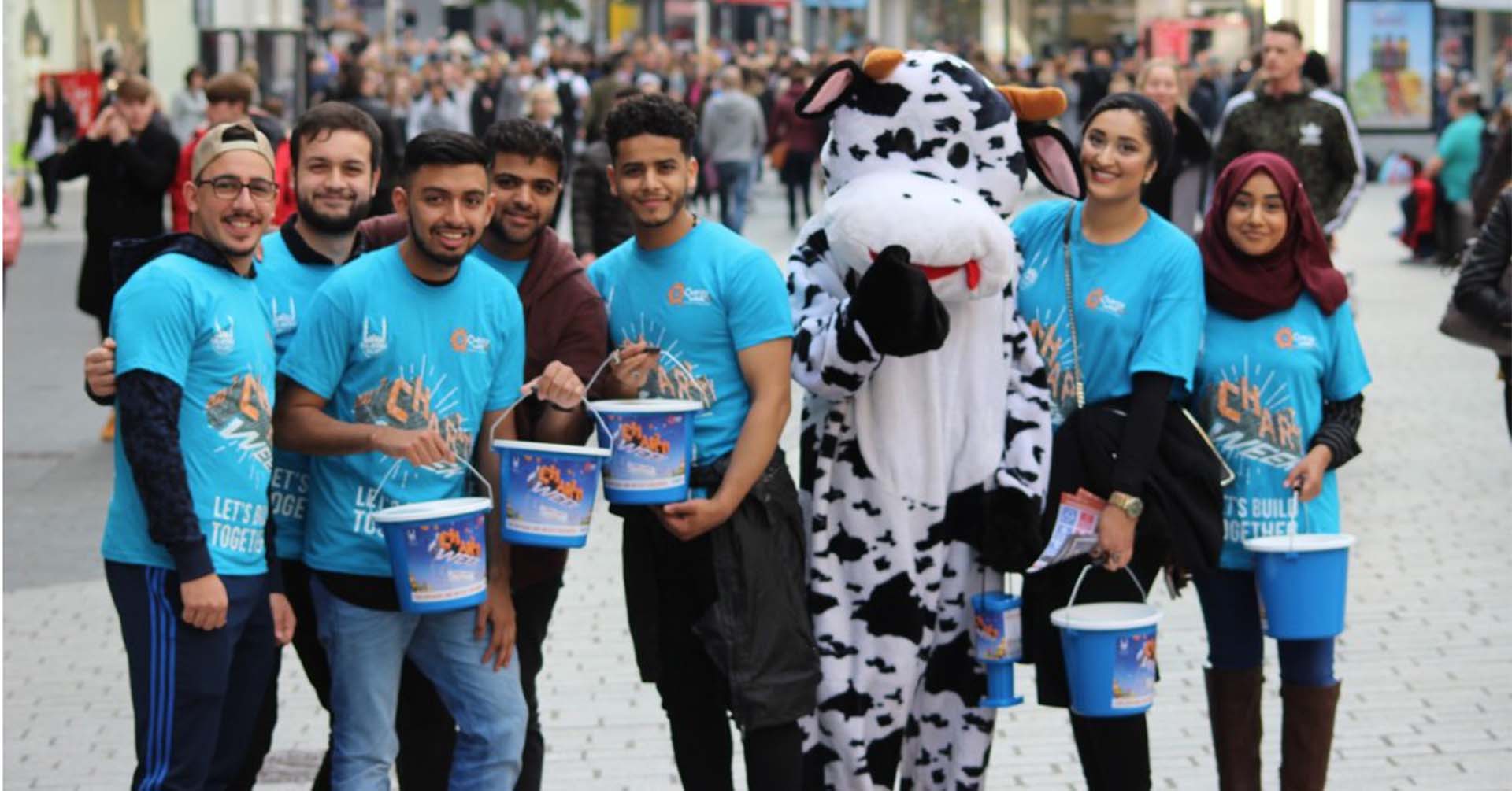 group of islamic relief volunteers holding money collection budgets and a cow mascot volunteering